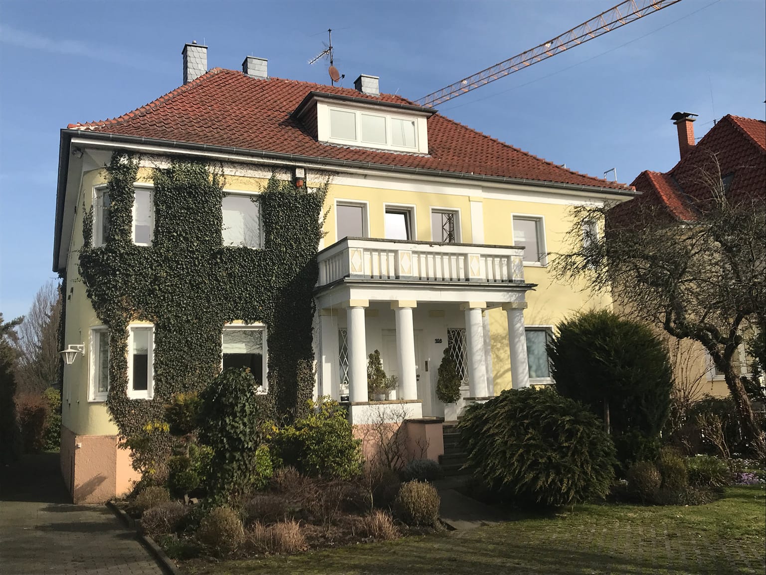 Institutsgebäude des WIBK in Paderborn: efeubewachsene gelbe Stadtvilla mit rotem Ziegeldach und Säulenportal